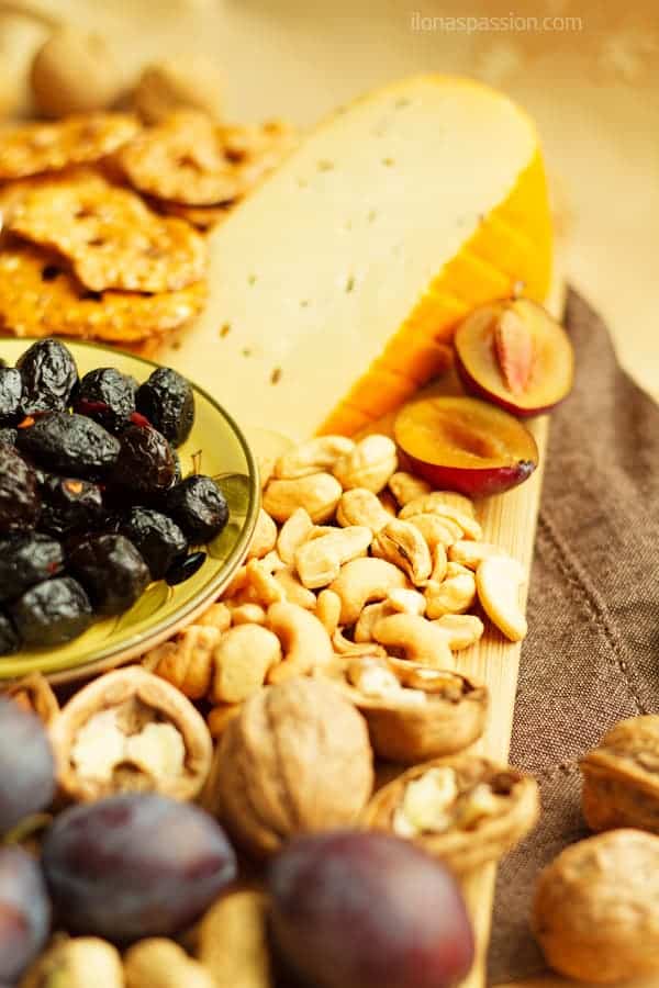 How to put together a cheese platter with pretzels, plums, olives and nuts.