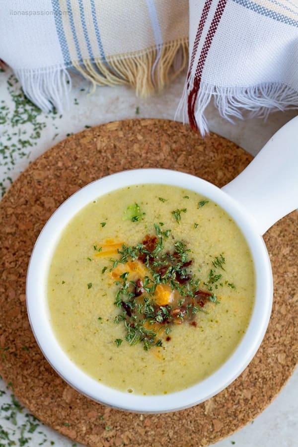 Broccoli cheddar soup with bacon served in a white bowl.