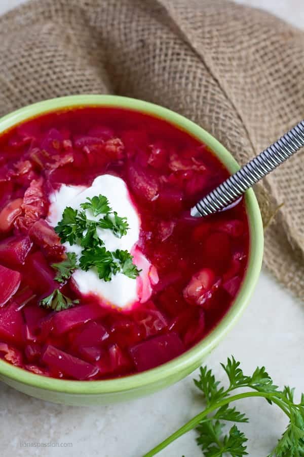 Beetroot soups topped with parsley served in a bowl.