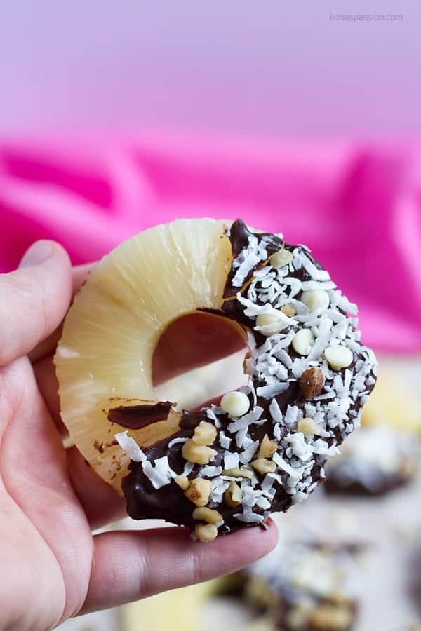 A pine apple ring dipped in melted chocolate and sprinkled with coconut and white candy chips