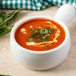 Homemade soup with tomatoes and fresh herb.