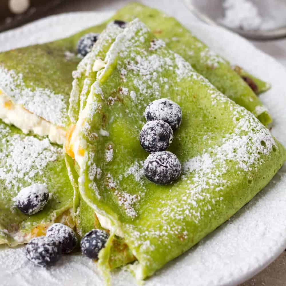 French crepes stuffed with farmer's cheese and mango. Colored green with fresh spinach