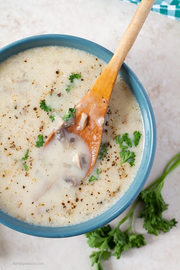 A A wooden spoon dipped in brownich thick homemade cream of mushroom soup.