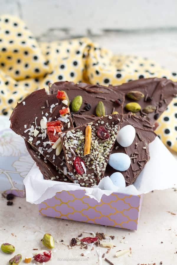 A gift idea basket of chocolate bark decorated with easter eggs, pretzels , cranberries and pistachios.