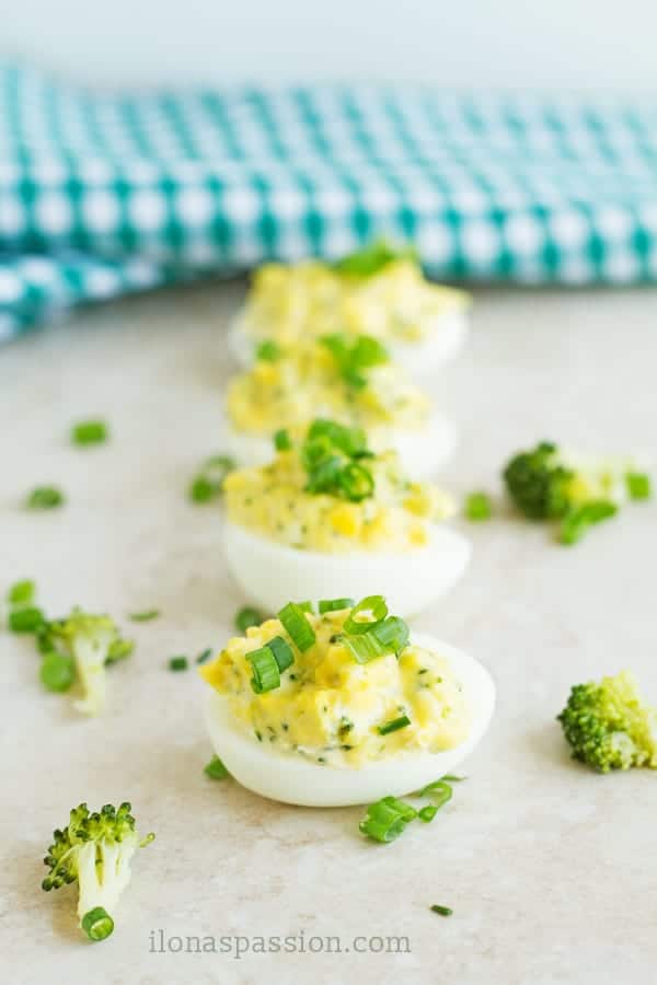 Few hard boiled egg stuffed with green veggies topped with chopped green onion.