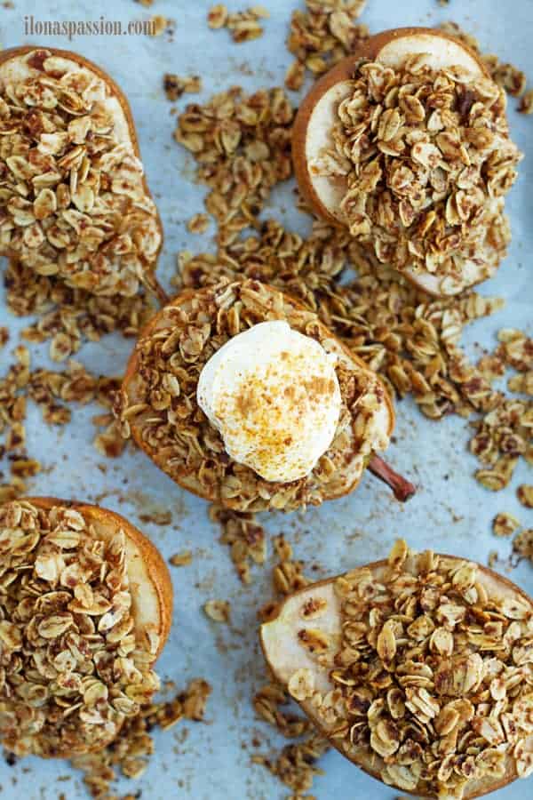 Granola stuffed roasted pear placed on baking sheet with parchment paper.