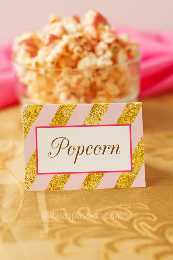 Pink and gold party decorations and ideas including table tent, popcorn with strawberry frosting.