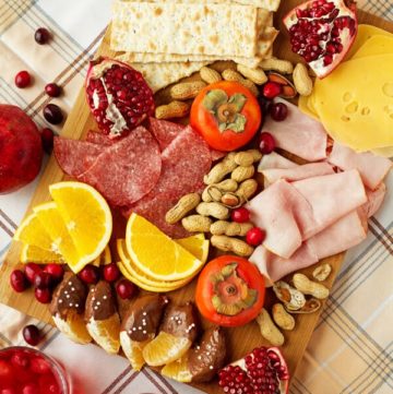 Winter appetizer platter including seasonal products including cranberries, oranges, cheese, persimmon, pomegranate, nuts, ham and salami by ilonaspassion.com I @ilonaspassion