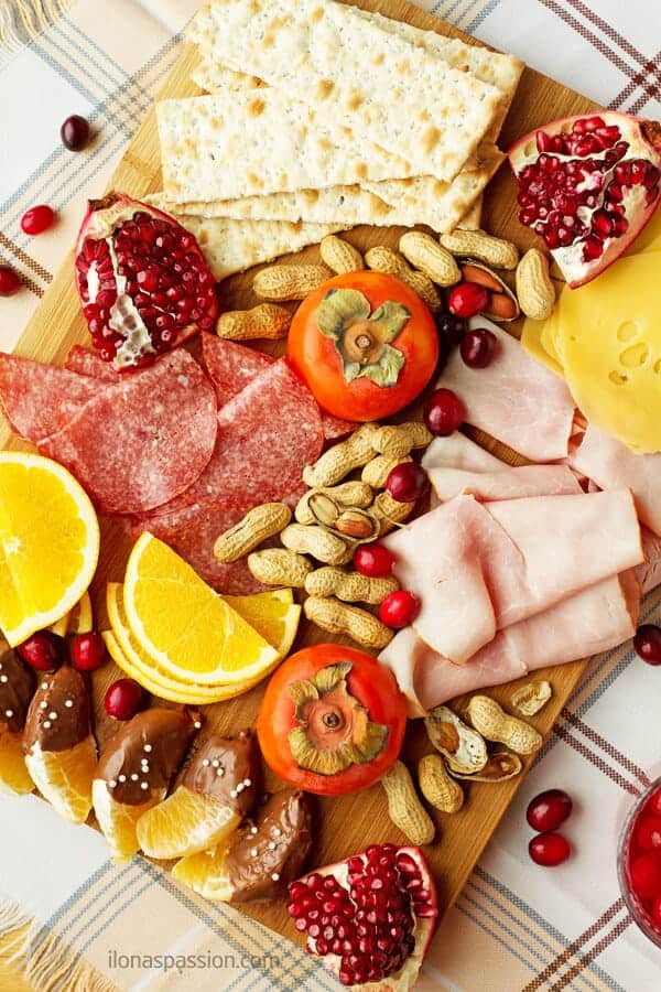 Winter appetizer platter including seasonal products including cranberries, oranges, cheese, persimmon, pomegranate, nuts, ham and salami by ilonaspassion.com I @ilonaspassion 