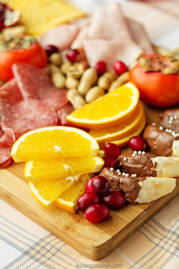 Winter appetizer platter including seasonal products including cranberries, oranges, cheese, persimmon, pomegranate, nuts, ham and salami by ilonaspassion.com I @ilonaspassion
