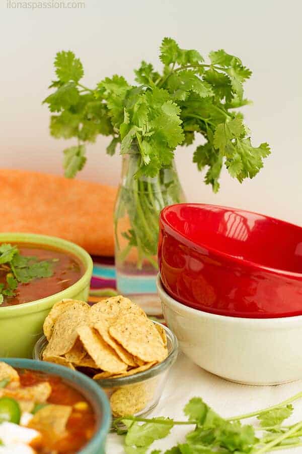 Fresh herb cilantro in a bottle, few empty bowls and tortilla chips prepared for party.