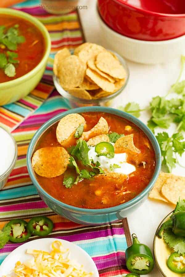 A bowl of hearty Mexican flavored soup served with tortilla chips, cheese, jalapeno and sour cream.