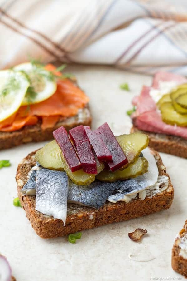 A bread topped with herring, pickles and roasted beets.