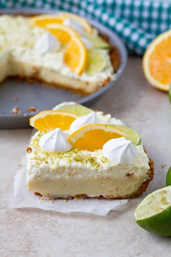 A slice of key lime pie with meringues and fresh citrus fruits.