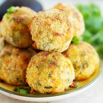 Stuck of arancini placed on a plate topped with green onion.