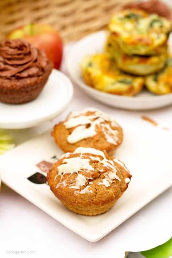 Banana muffins on a plate with chocolate cake in the back.