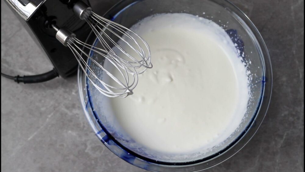 Whipping cream with powdered sugar and mixer.