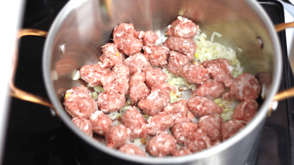Onion and Italian sausage in a pan.