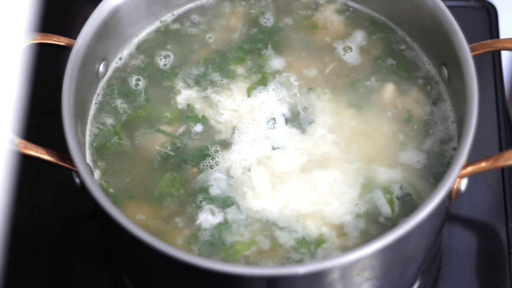 Adding heavy cream to stock to make Zuppa toscana soup.