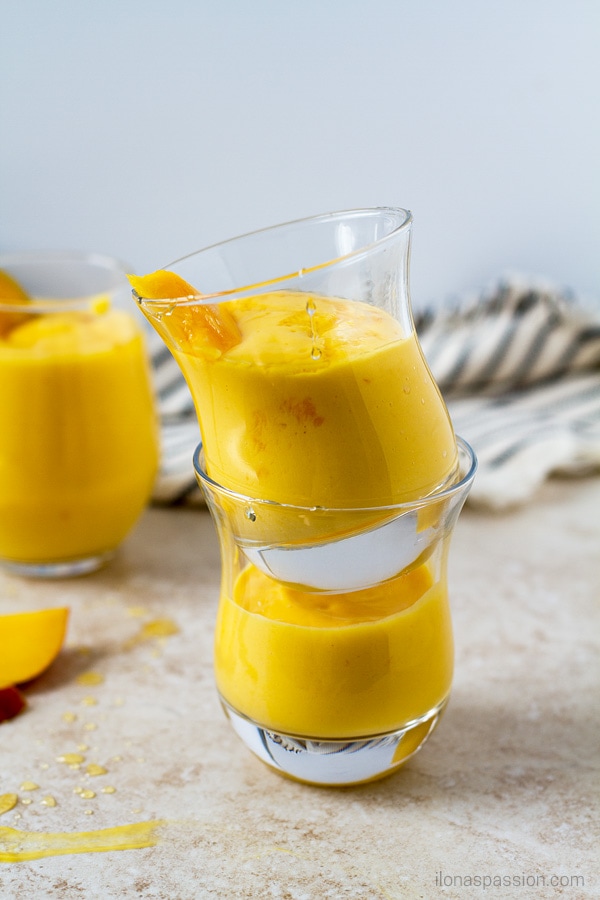 Sweet mango lassi drink topped with honey and fresh mango slice.