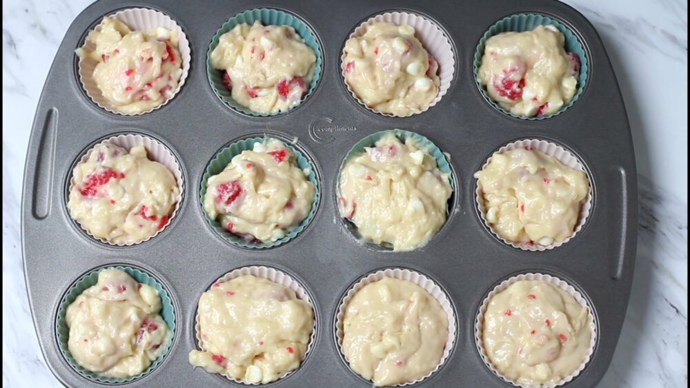 Muffins batter in liners in baking pan before baking.