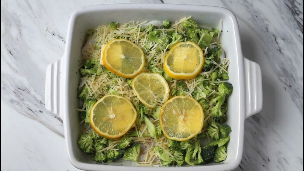 Raw white fish topped with broccoli, parmesan and lemon slices.