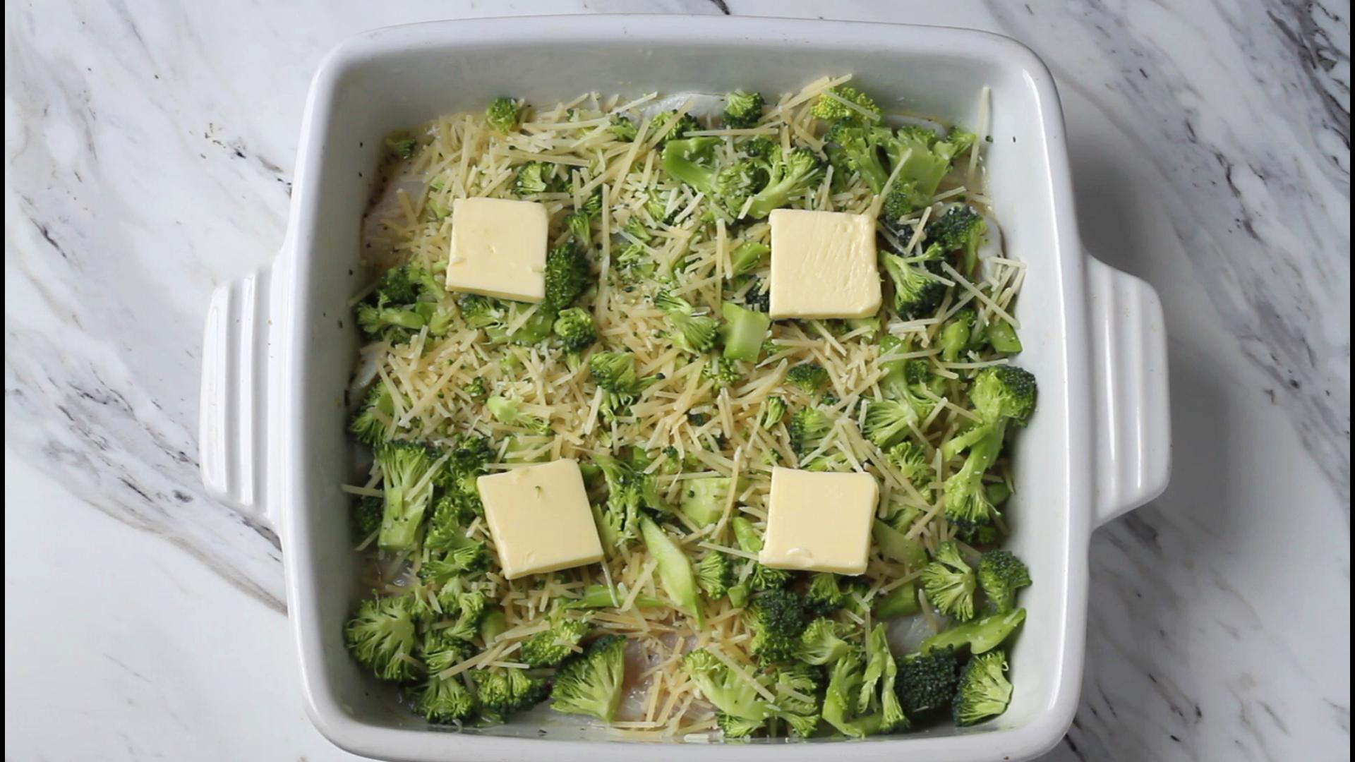 Raw fish with broccoli, shredded cheese and slices of butter.
