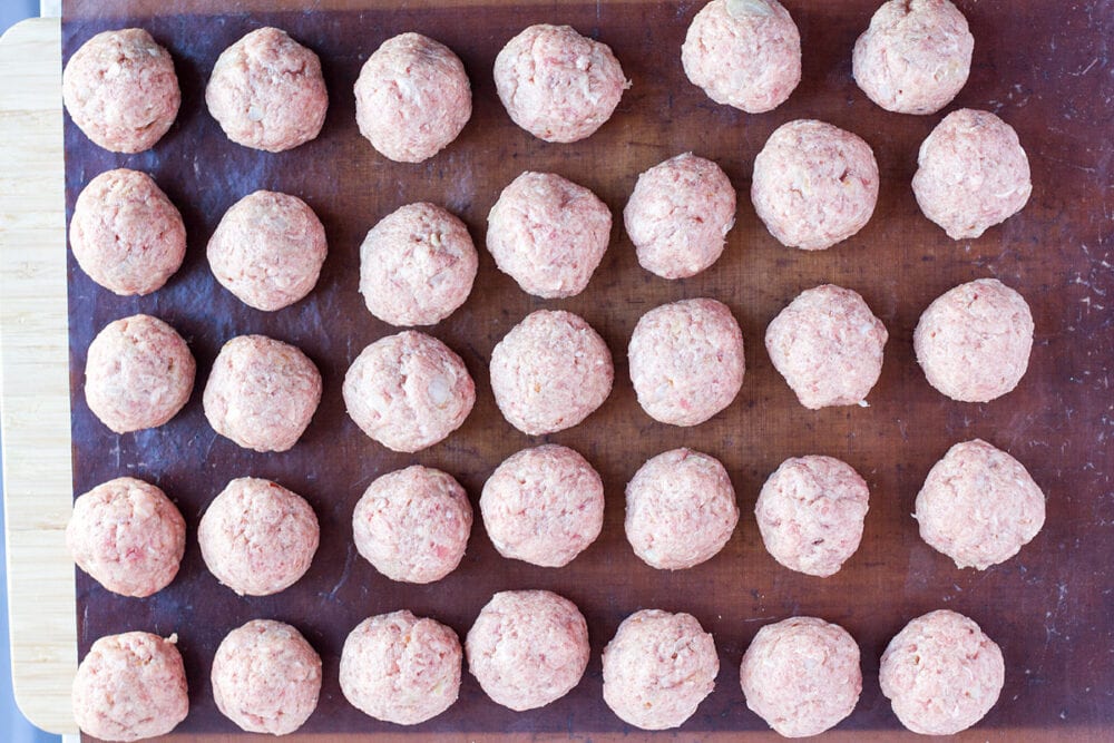 Uncooked meatballs kottbullar placed on baking sheet.