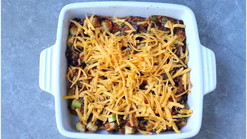 Taco dish with quinoa topped with cheddar cheese, unbaked.