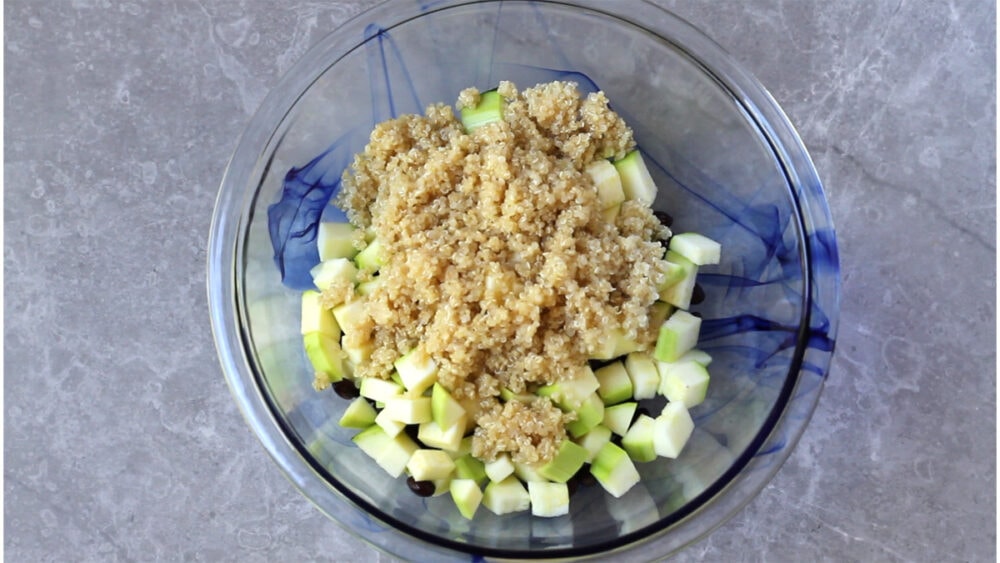 Diced zucchini, cooked quinoa in a bowl.